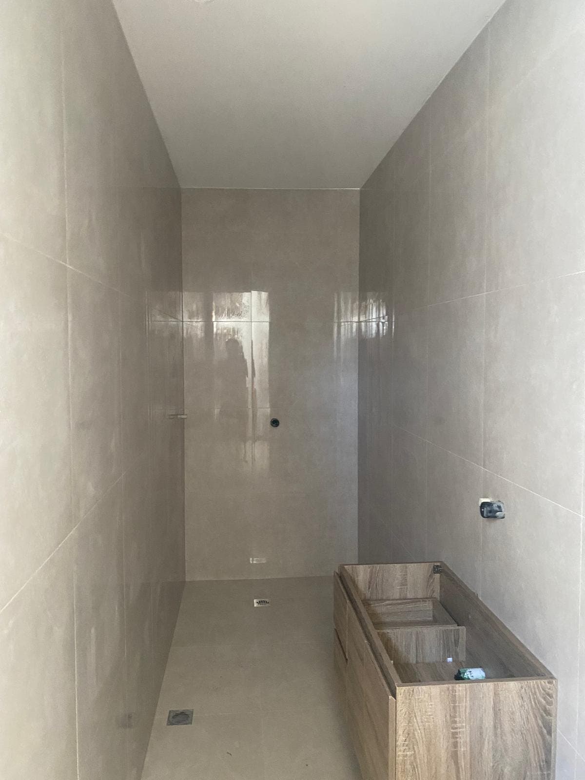 Renovation photo: shower wall tiled in large grey tiles